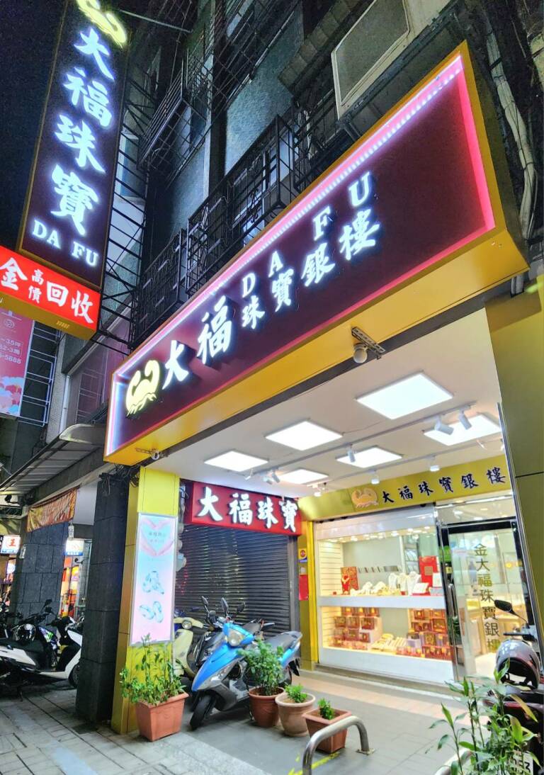 大福珠寶銀樓三和路店面夜景：霓虹燈的「大福珠寶銀樓 DA FU」招牌，下方是亮著的展示櫃